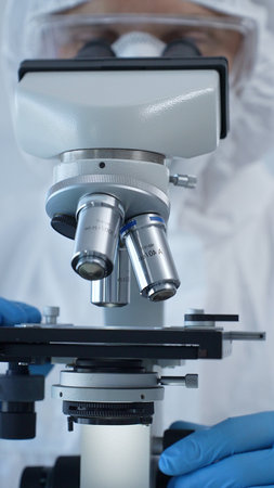Close up of medical virologist in a hazmat suit, mask, and gloves, diligently working at a...