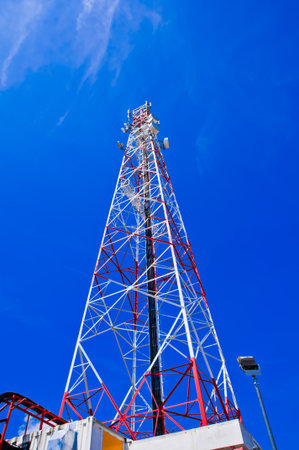Red and white tower of communications with with a lot of different antennas under clear sky  の写真素材