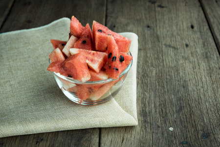 Cut watermelon in a bowl placed on a wooden backgroundの写真素材