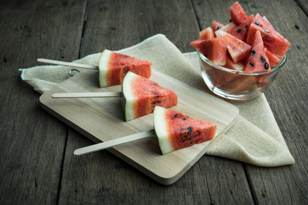 Cut watermelon in a bowl placed on a wooden backgroundの写真素材