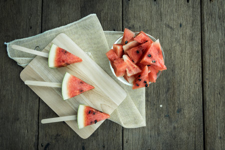 Watermelon cut into pieces on wooden floor.の写真素材