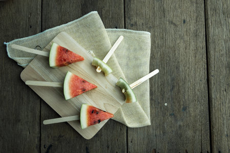 Watermelon cut into pieces on wooden floor.の写真素材