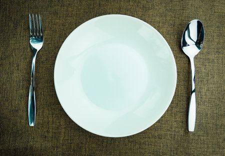 Placing a spoon and fork on a plate at a dining table.の写真素材