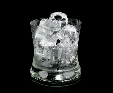 Glass and ice with whiskey on black background.の写真素材