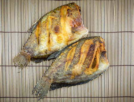 Fried fish cooked and placed on old wooden floor.の写真素材