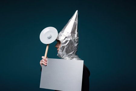 Alu has protester talking, conspiracy theories, tin foil on the head, holding an empty sign, conversation and communication conceptの素材