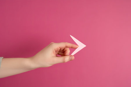 Holding an arrow in the hand, symbol for growth, success and development, pink colored background, copy space for textの素材