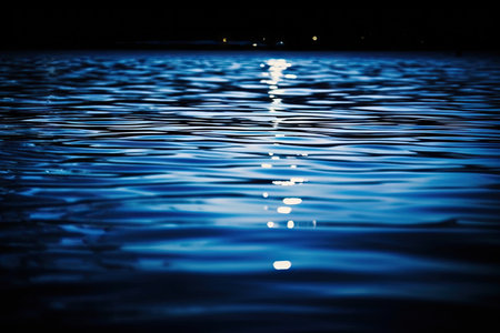 reflection of light on the surface of the water night time little waves navy blue marine background with space for designの素材