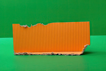 a piece of orange corrugated cardboard with torn edges on a green background bright modern background with copy space for textの素材
