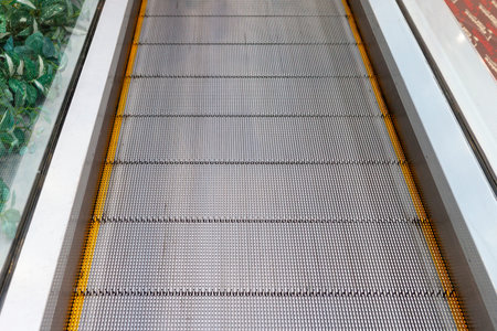 Escalator without stairs in a shopping mall. Moving down staircase. Close up metal platform. Top...
