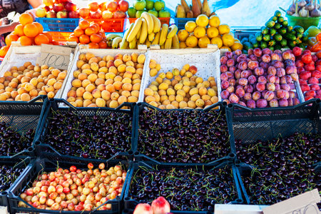 Street fruit and vegetable store counter with crates. Crates of cherry, cherries, plum, apricot, banana, cucumber. Heap of berries. Trade tent.の写真素材