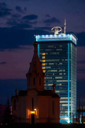 Tolyatti, Russia, April 24, 2006: White church on the background of the main office of VAZ. Volzhsky Avtomobilny Zavod. Beautiful evening blue sky.のeditorial素材