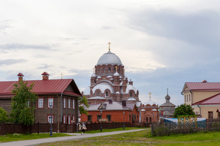 Sviyazhsk, Russia, June 04, 2018: Cathedral in the name of the icon of the Mother of God. Wooden village house near the temple. Gray domes, golden crosses.のeditorial素材