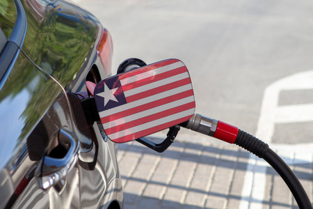 Flag of Liberia on the car's fuel tank filler flap. Fueling car with petrol pump at a gas station. Petrol station. Gasoline and oil products. Close up.の写真素材