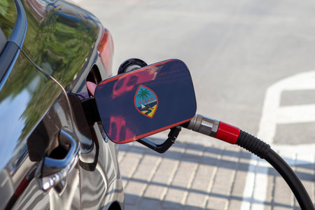Flag of Guam on the car's fuel tank filler flap. Fueling car with petrol pump at a gas station. Petrol station. Gasoline and oil products. Close up.の写真素材