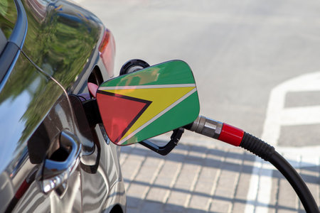 Flag of Guyana on the car's fuel tank filler flap. Fueling car with petrol pump at a gas station. Petrol station. Gasoline and oil products. Close up.の写真素材