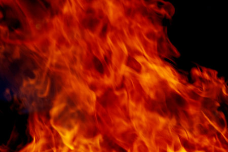 Red flames on black background. Texture of fire. Bonfire for burning of garbage, cooking. Close up.