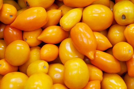 Heap of fresh ripe orange tomatoes without branches. Useful yellow vegetable for salads, pizza, sauces, salsa, ketchup. Top view. Close up.の写真素材