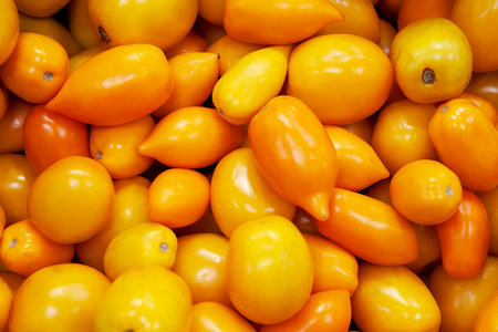 Heap of fresh ripe orange tomatoes without branches. Useful yellow vegetable for salads, pizza, sauces, salsa, ketchup. Top view. Close up.の写真素材