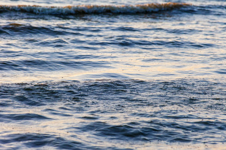 Waves on the sandy shore of a large river. The rays of light are reflected in the waves,の写真素材