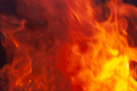 Red flames on black background. Texture of fire. Bonfire for burning of garbage, cooking. Close up.の写真素材