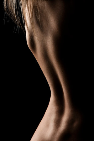 Beautiful woman's back on black isolated. Nude sensual woman back in the light.の写真素材