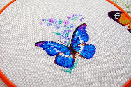 Colorful pattern of butterfly with flower embroidered on fabric close-upの写真素材