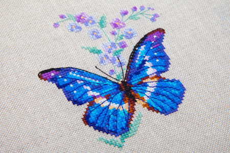 Colorful pattern of butterfly with flower embroidered on fabric close-upの写真素材