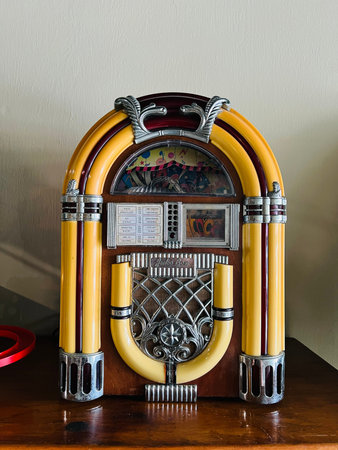 Colorful vintage jukebox featuring chrome accents, curved tubes, decorative grille, and song list...