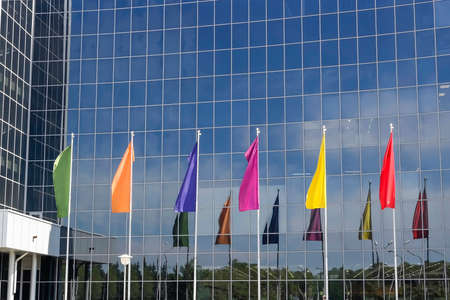 six multicolored flags against the background of the office buildingの写真素材