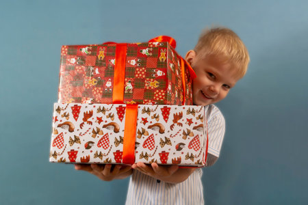 a boy in a shirt on a blue backgroundholds a gift in his hands