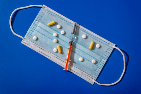 medical face mask,tablets,a syringe lying on a blue background.Coronavirus disease or corona virus concept.の写真素材