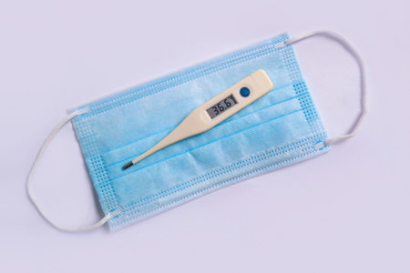 the temperature is 36.6 on the thermometer that lies on the medical mask