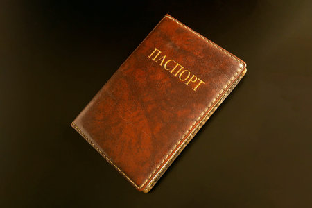 the Russian passport in a brown leather cover lies on a black background