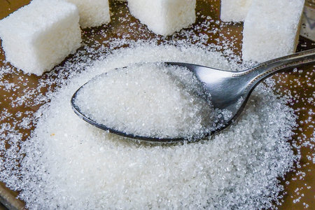 someone adds sugar to a cup of tea.