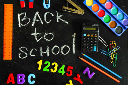 the inscription back to school on the blackboard among the school suppliesの写真素材