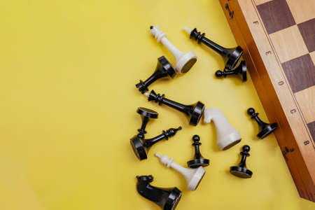 chess pieces are scattered on a yellow background next to the chessboard,の写真素材
