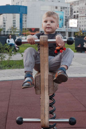 a little boy plays on a children's attraction at a children's city playground.の写真素材