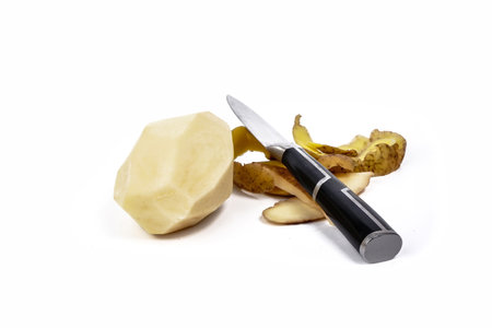 peeled potatoes lie isolated on a white background, and there is a peel and a knifeの写真素材