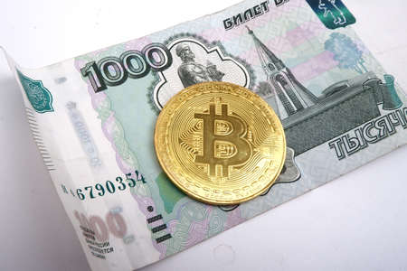 one bitcoin and one thousand rubles lie side by side on a white background.の写真素材