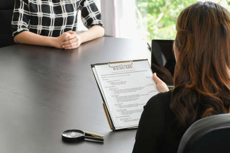 Recruitment. The employer is interviewing with women in the office. Close-up of Resume on business concept.の写真素材