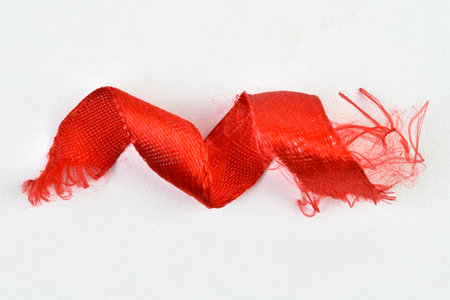 Close up to Shabby Red Ribbon isolated on white background. Red ribbon decoration. Birthday ribbon. Red ribbon dirty isolated view.の写真素材