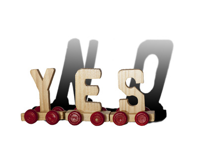 Three wooden letters on wheels make the word YES and the shadow of them is NO, isolated on white backgroundの写真素材