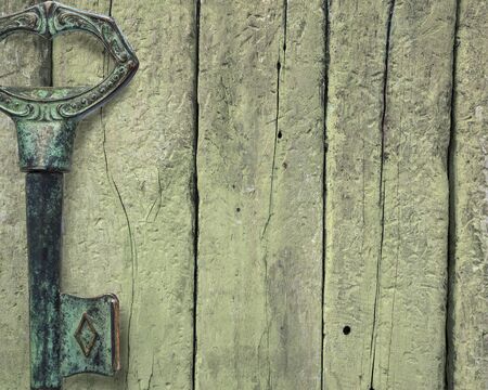 Close up of old metal green key on wooden background with copyspace on the right sideの写真素材