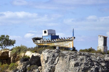 Old rusty fishing boat laying on a rockの写真素材