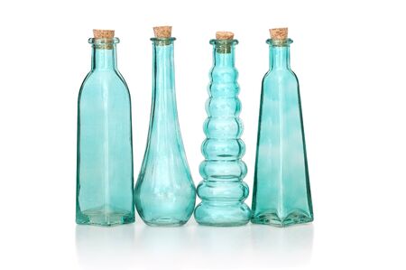 Row of four cyan colored corked empty glass bottles of different shapes, isolated on whiteの写真素材