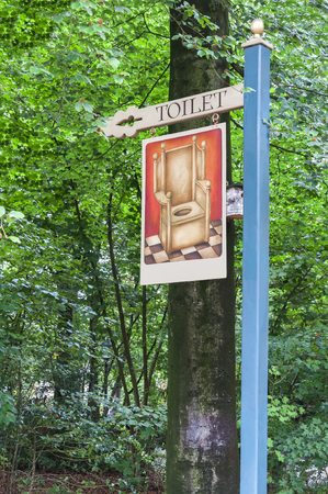Unusual wooden signpost in a park, showing the way to the public toiletの写真素材