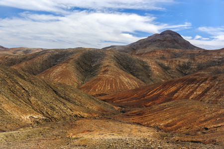 Spectacular coloring and structure of a rural park of Betancuria in Fuerteventura, one of the Canary Islands. The terrain is formed by a line up of hills with rounded summits, which steeply slope down to the bottom of the ravines.の写真素材