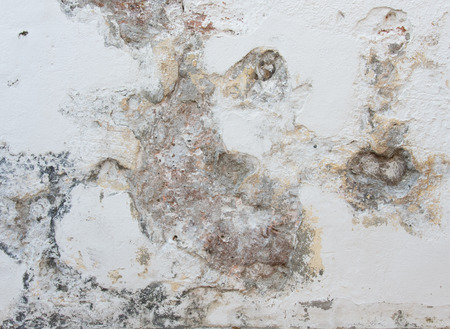 Old concrete weathered wall covered with white stucco finishingの写真素材