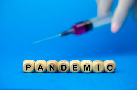 The sign Pandemic on wooden cubes and syringe.Medical concept, epidemic diseasesの写真素材